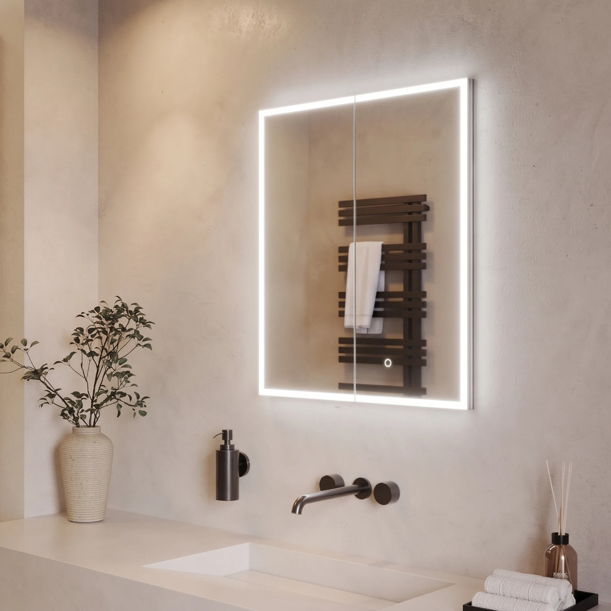 A modern rectangular bathroom mirror with a bright white LED light border, mounted on a textured beige wall above a white sink with a matte black faucet. The mirror reflects a dark wood heated towel rail with a white towel. #Size_600mm x 700mm