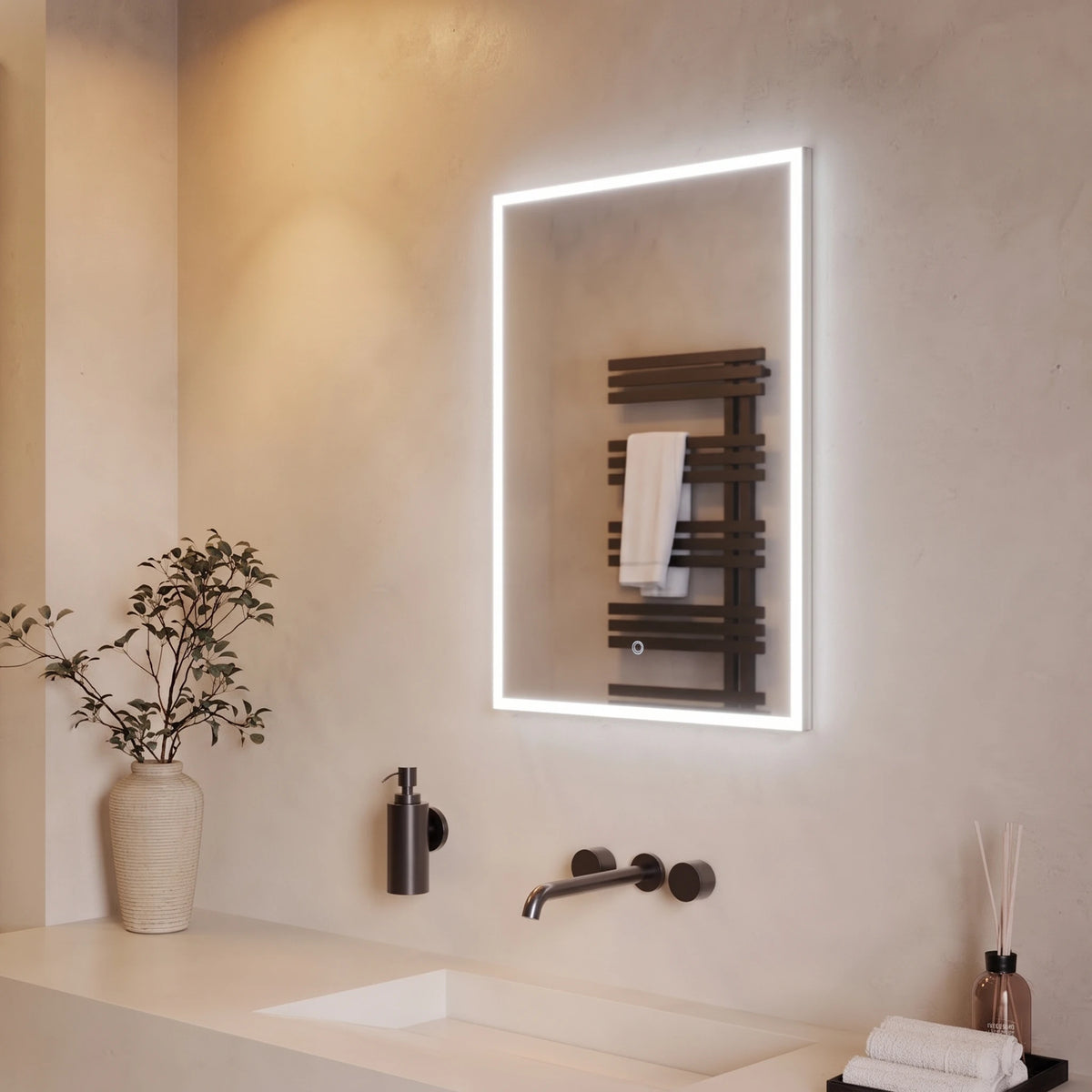 A modern rectangular wall-mounted mirror with a glowing white LED light frame, installed above a bathroom vanity. The mirror reflects a dark wood heated towel rail with a white towel. #Size_500mm x 700mm