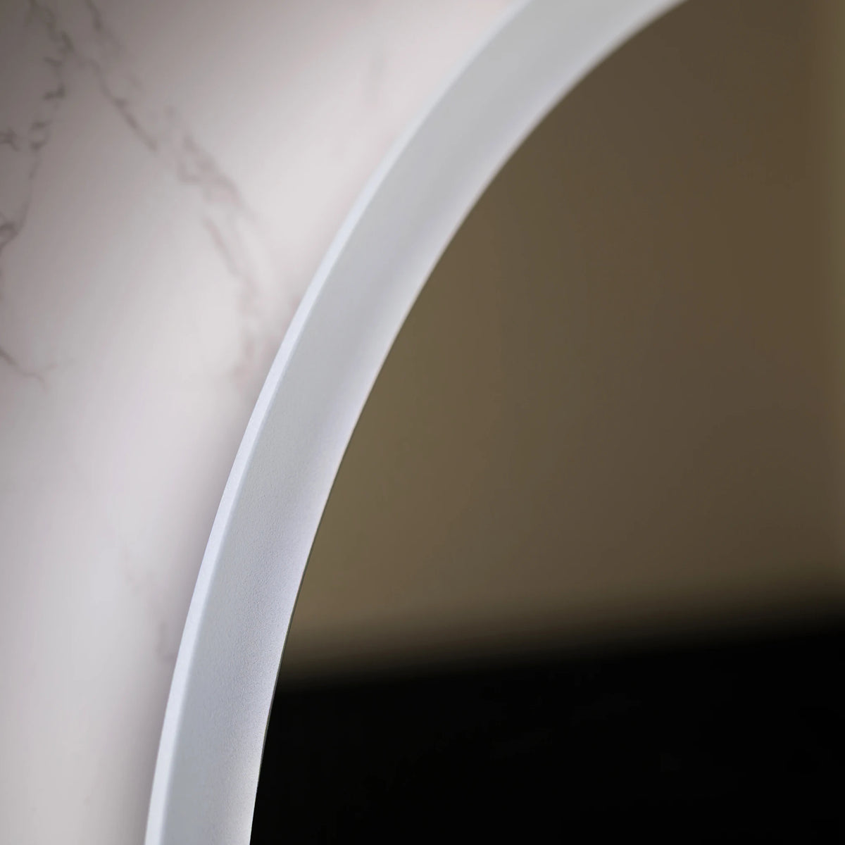 Close-up of a white arched product, possibly a lamp base or decorative trim, against a beige background with a dark reflective area below.